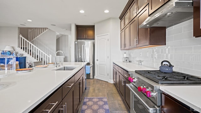 kitchen with dark brown cabinetry, sink, tasteful backsplash, wood-type flooring, and appliances with stainless steel finishes