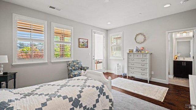 bedroom featuring dark hardwood / wood-style floors, ensuite bathroom, and multiple windows