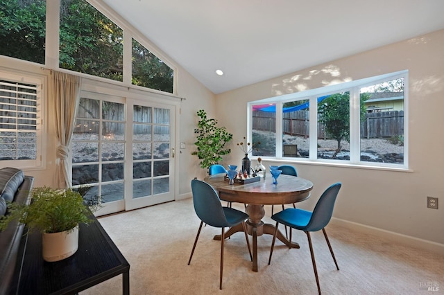 carpeted dining space with high vaulted ceiling