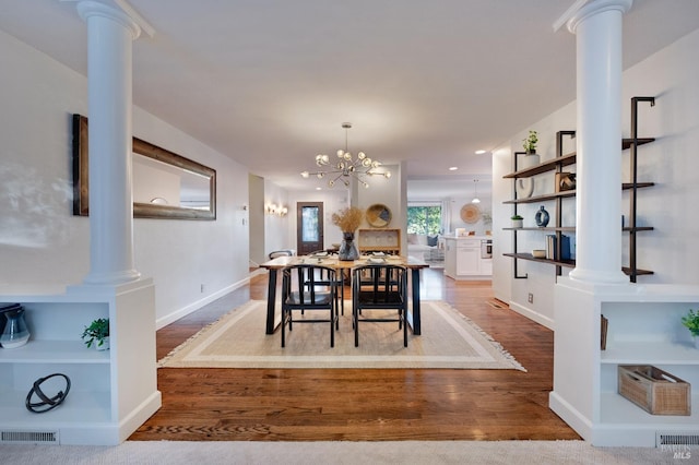 dining space with ornate columns, an inviting chandelier, and wood-type flooring