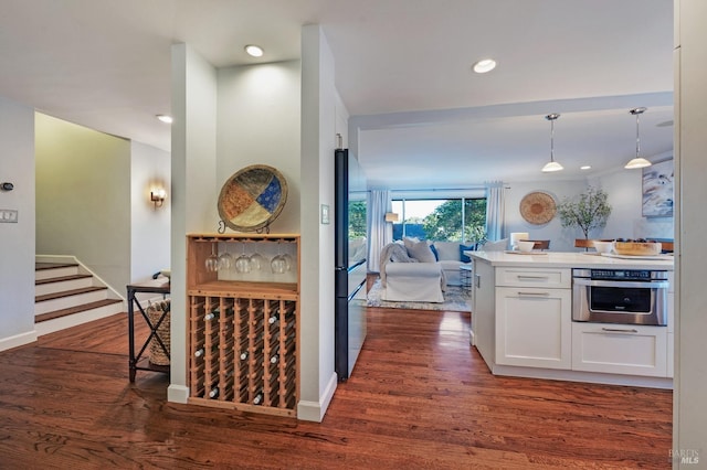 kitchen with decorative light fixtures, stainless steel appliances, dark hardwood / wood-style floors, and white cabinetry