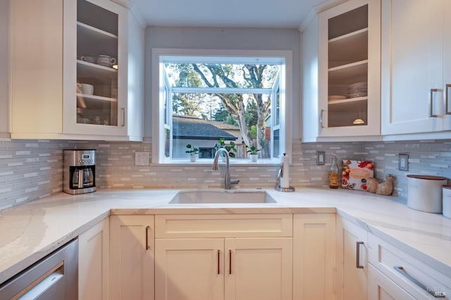 kitchen featuring light stone countertops, white cabinets, sink, and tasteful backsplash