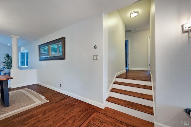 stairs featuring decorative columns and hardwood / wood-style flooring