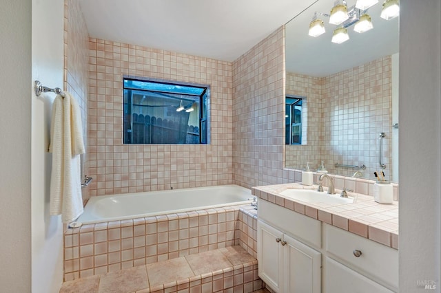 bathroom featuring tile walls, vanity, and tiled bath