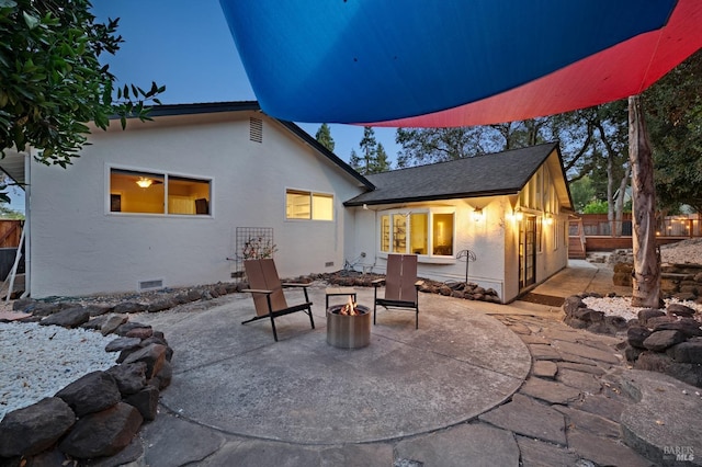 back house at dusk featuring an outdoor fire pit and a patio