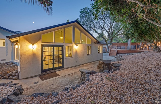 back house at dusk featuring a patio and a deck