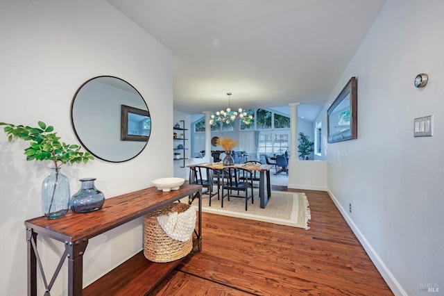 hall featuring a notable chandelier, lofted ceiling, and dark wood-type flooring