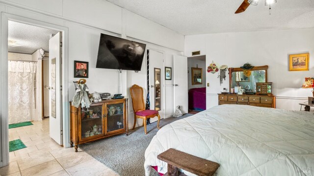 tiled bedroom with lofted ceiling, ensuite bathroom, a textured ceiling, and ceiling fan