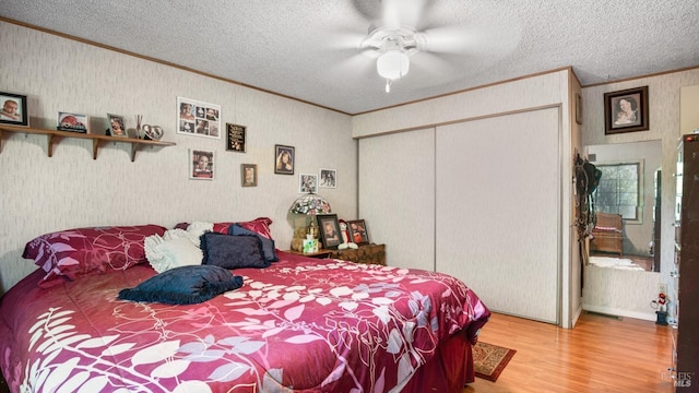 bedroom featuring crown molding, hardwood / wood-style floors, a textured ceiling, and ceiling fan