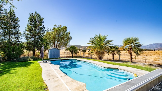 view of swimming pool with a mountain view, a storage unit, and a lawn