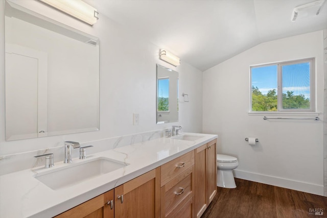 bathroom with hardwood / wood-style floors, vaulted ceiling, toilet, and vanity