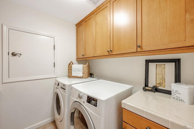 clothes washing area featuring washing machine and clothes dryer and cabinets