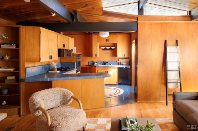 kitchen with tile counters, lofted ceiling with beams, light hardwood / wood-style flooring, and stainless steel appliances