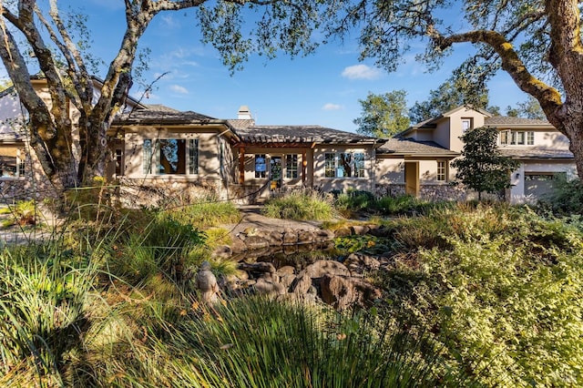 rear view of property with a garage, a chimney, and stucco siding