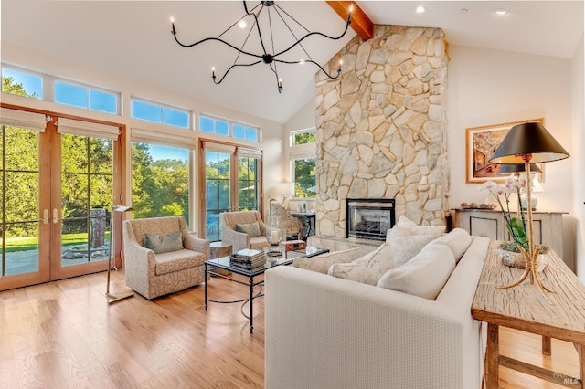 living room with high vaulted ceiling, an inviting chandelier, a stone fireplace, light wood-style floors, and beamed ceiling