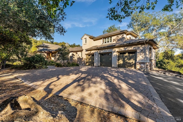 view of front of house featuring a tile roof, a garage, stucco siding, and decorative driveway