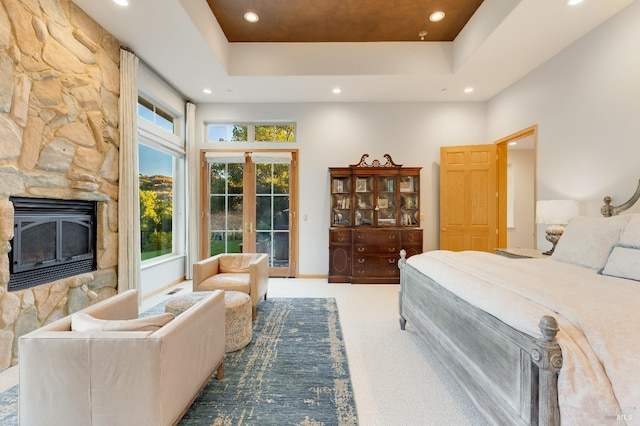 carpeted bedroom with a tray ceiling, recessed lighting, french doors, a fireplace, and access to exterior