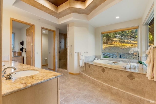 bathroom with a tray ceiling, a shower stall, tile patterned floors, a garden tub, and vanity
