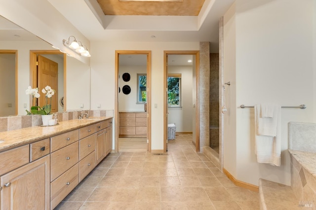 bathroom with tile patterned floors, a raised ceiling, baseboards, tiled shower, and vanity