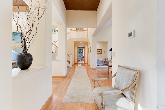 interior space featuring stairway, wood finished floors, baseboards, and a towering ceiling