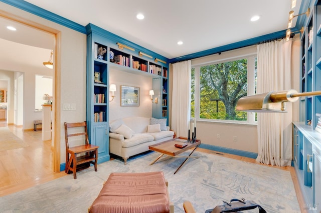 sitting room with built in shelves, light hardwood / wood-style flooring, and crown molding