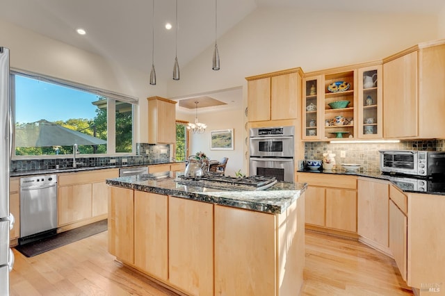 kitchen featuring a center island, light brown cabinets, appliances with stainless steel finishes, and dark stone counters