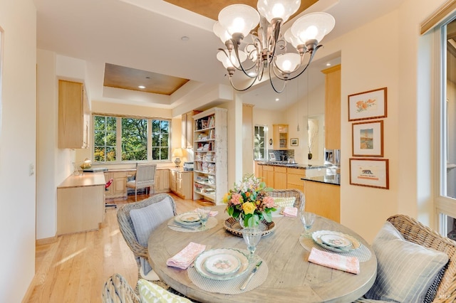 dining area featuring recessed lighting, a notable chandelier, light wood-style flooring, and a tray ceiling