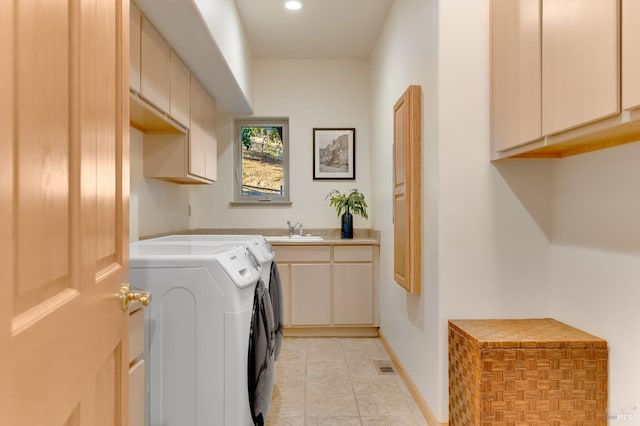 clothes washing area with washing machine and dryer, sink, and cabinets