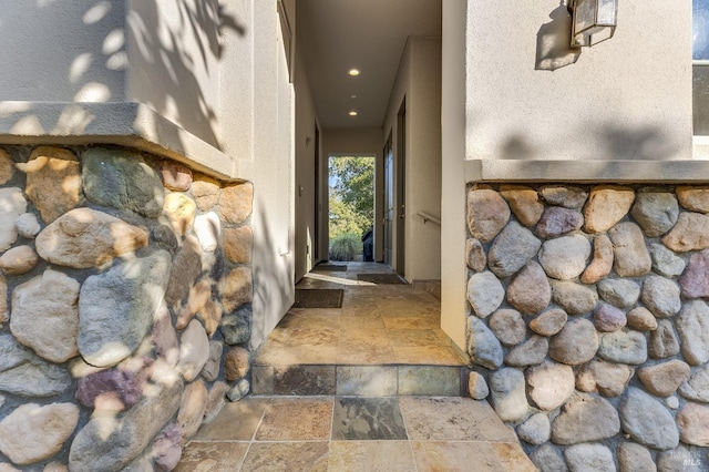 property entrance with stone siding and stucco siding