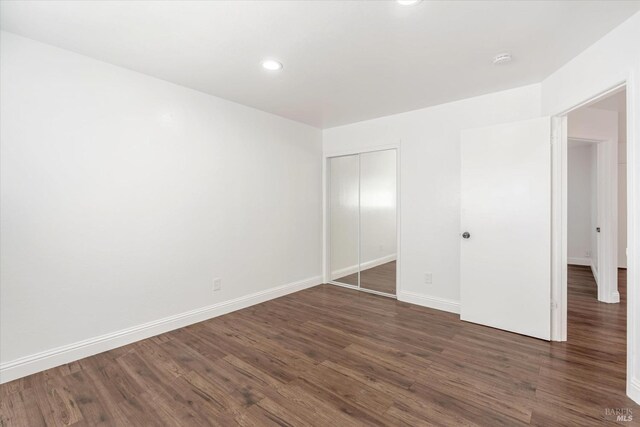 unfurnished bedroom featuring dark wood-type flooring and a closet