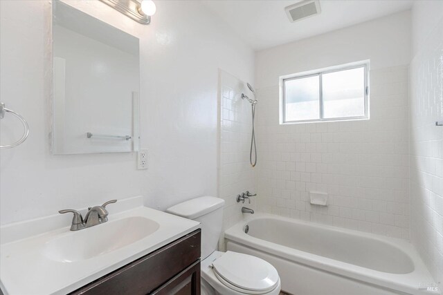 full bathroom featuring tiled shower / bath, vanity, and toilet