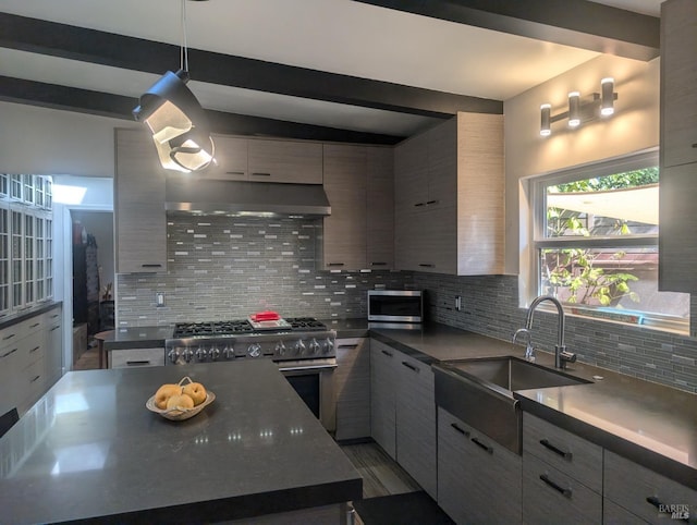 kitchen featuring pendant lighting, tasteful backsplash, high end stainless steel range oven, and sink