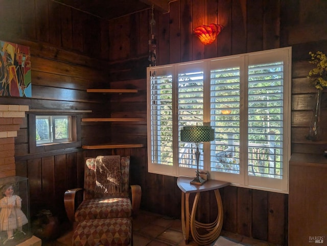 sitting room with wood walls and tile patterned floors