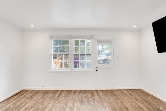 empty room featuring a healthy amount of sunlight, light hardwood / wood-style flooring, and ornamental molding