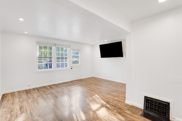 unfurnished living room with ornamental molding and light hardwood / wood-style floors