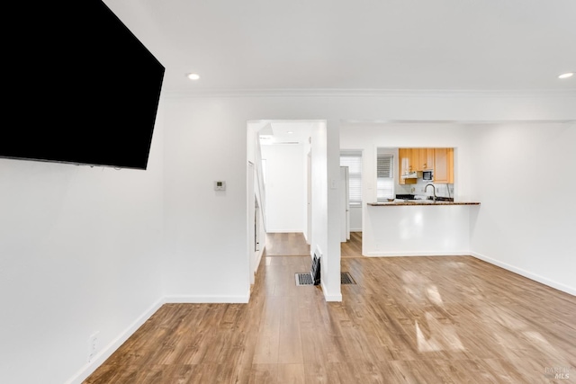 unfurnished living room featuring light wood-type flooring and ornamental molding