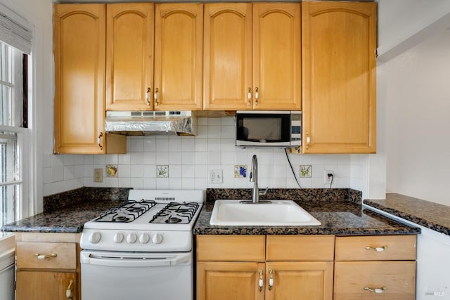 kitchen featuring gas range gas stove, backsplash, sink, and dark stone countertops