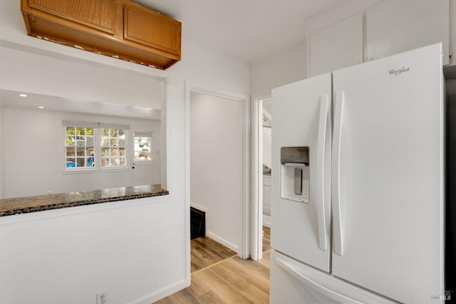 kitchen with light hardwood / wood-style floors, dark stone countertops, and white fridge with ice dispenser