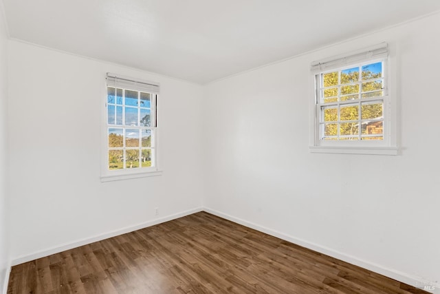 spare room featuring dark hardwood / wood-style floors, plenty of natural light, and crown molding