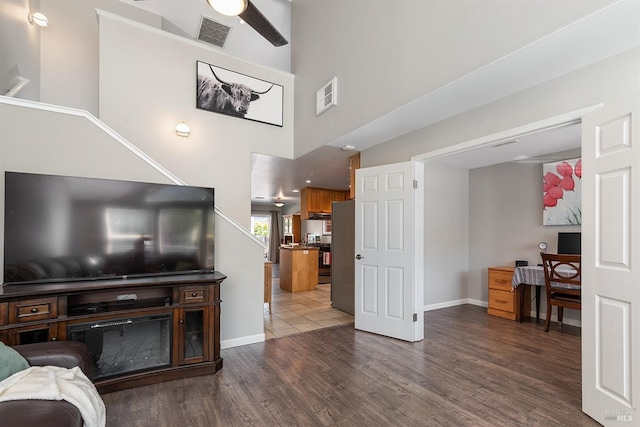 living room featuring ceiling fan, dark hardwood / wood-style flooring, and a towering ceiling