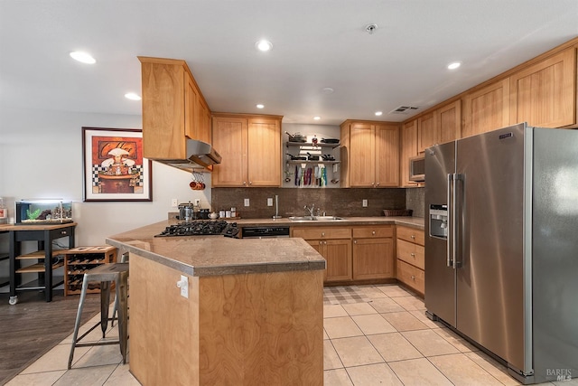 kitchen featuring kitchen peninsula, a breakfast bar, light tile patterned flooring, and stainless steel appliances