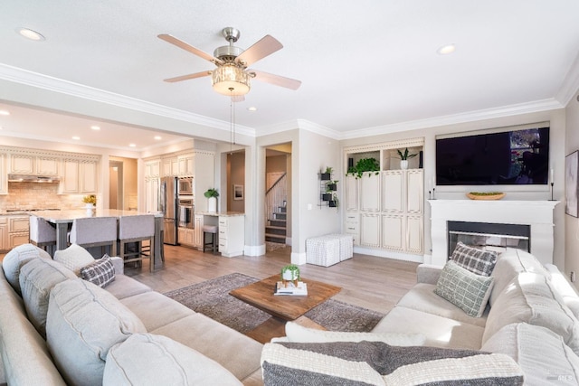 living room featuring ceiling fan, ornamental molding, and light hardwood / wood-style floors