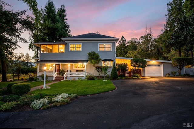 view of front of property featuring a garage, a yard, and covered porch