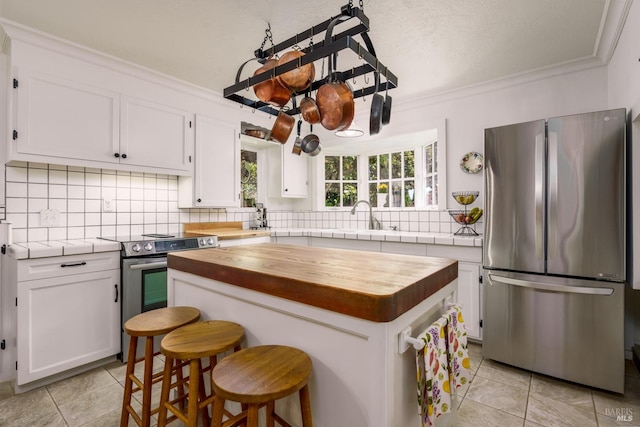 kitchen featuring tasteful backsplash, crown molding, white cabinets, appliances with stainless steel finishes, and a center island