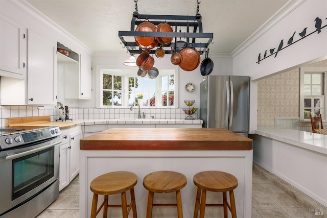 kitchen with wood counters, decorative backsplash, stainless steel appliances, and white cabinets