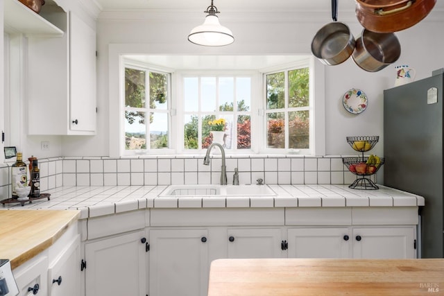 kitchen with hanging light fixtures, a healthy amount of sunlight, white cabinets, and tile counters