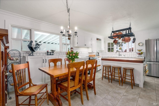 dining area featuring light tile patterned floors, sink, crown molding, and a chandelier