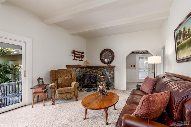 living room with a wood stove, beam ceiling, and light colored carpet