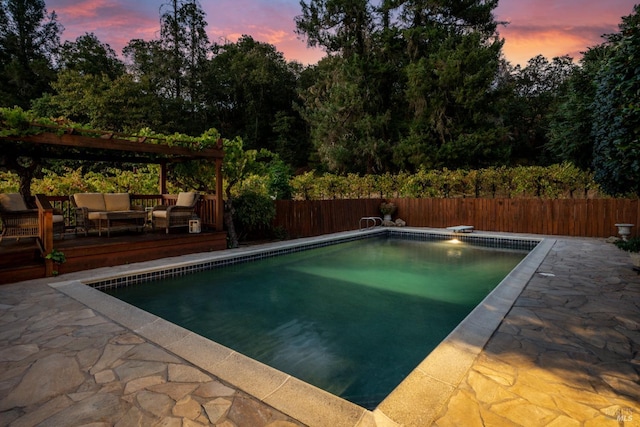 pool at dusk with an outdoor living space, a wooden deck, and a diving board