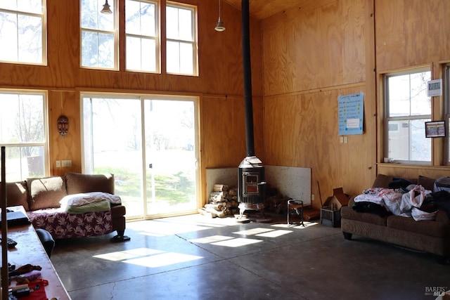 interior space featuring concrete flooring, a high ceiling, and a wood stove